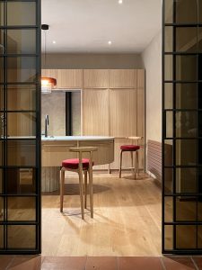 Cucina vista dall’ingresso con isola e sedute su misura