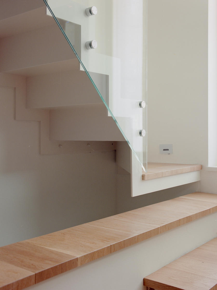 Dettaglio scala in vetro sospesa e gradino come mensola