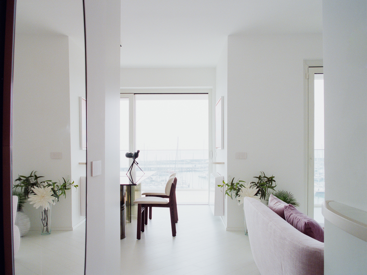 Zona giorno dell’attico a Varazze con cucina a isola e arredi su misura affacciati sul porto