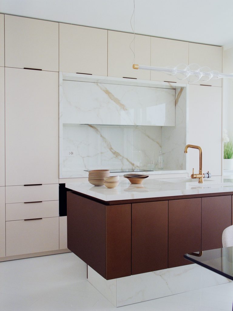 Dettaglio della cucina con isola in marmo Calacatta e pensili su misura nell’attico di Varazze