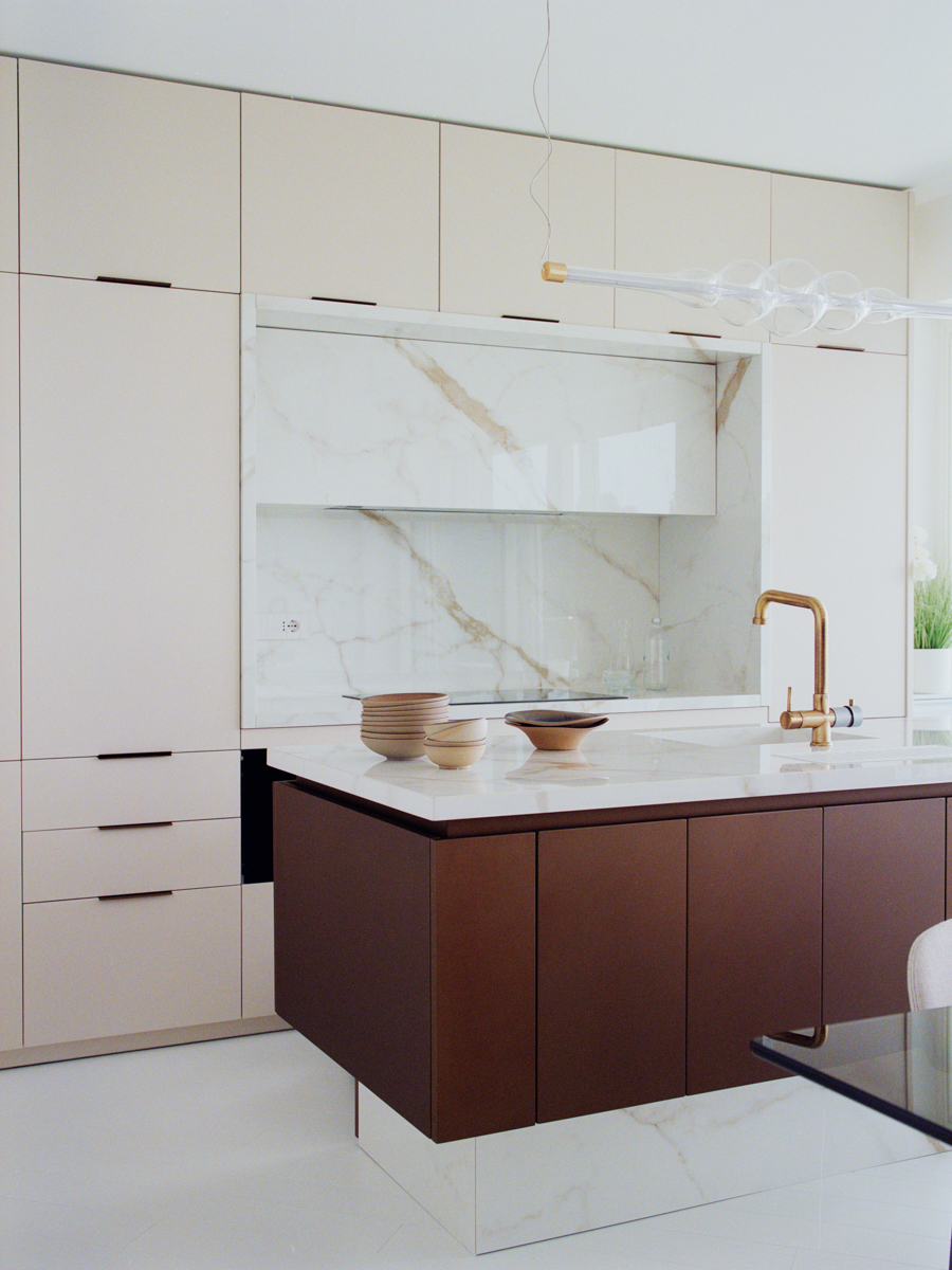 Dettaglio della cucina con isola in marmo Calacatta e pensili su misura nell’attico di Varazze