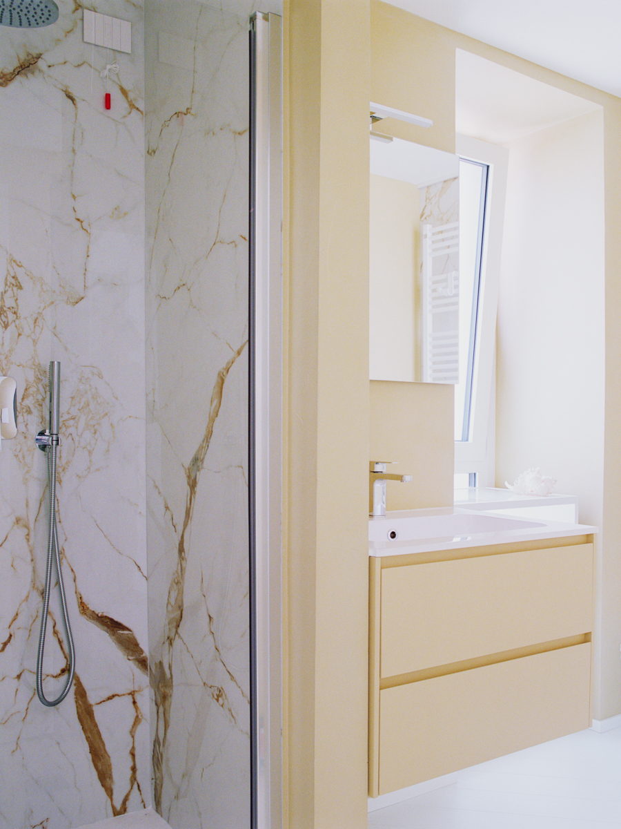 Bagno dell’attico a Varazze con rivestimenti in marmo Calacatta e arredi su misura