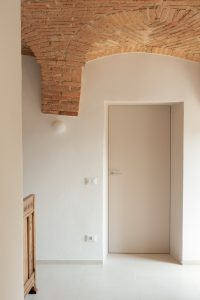 Dettaglio di porta e muratura storica con volta in mattoni a vista