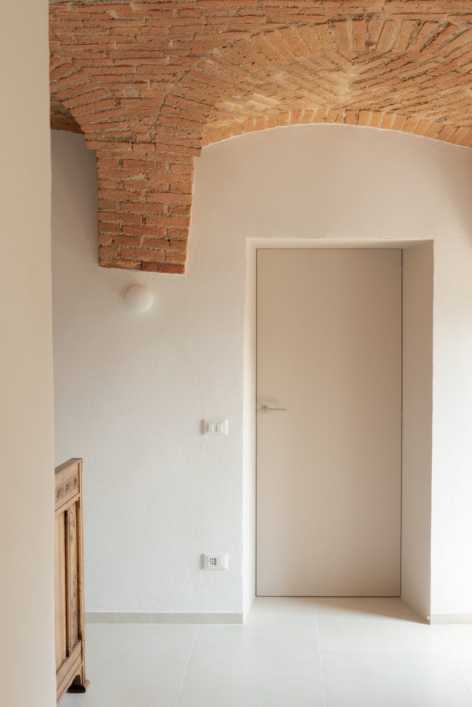 Dettaglio di porta e muratura storica con volta in mattoni a vista